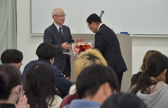 講義終了後、飯尾良英・人間福祉学部学部長から花束を贈られる古田さん