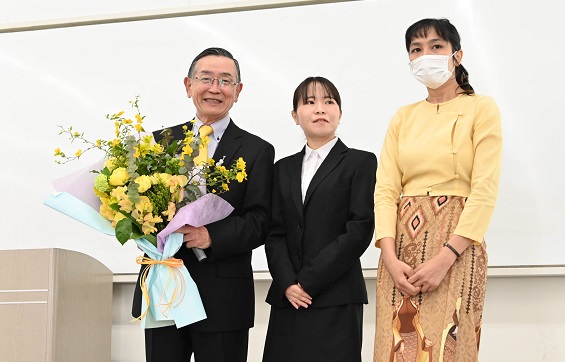 感謝のセレモニーでお礼の言葉を述べ、花束を贈る奨 学生代表ら