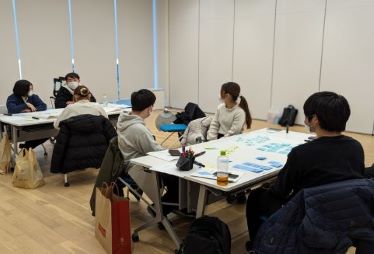 参加者学生が2グループに分かれてワークショップを行なうなかで、一人の参加者の話を聞く様子の写真